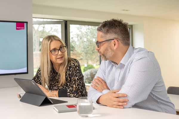 Two colleagues sit at a laptop in discussion
