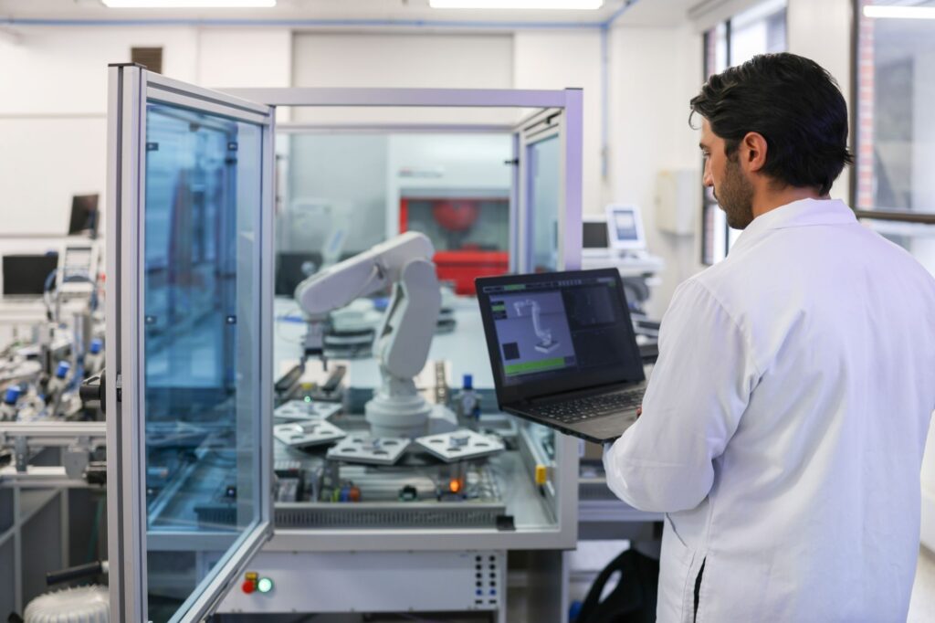 A man stands behind a computer in a modern manufacturing laboratory of innovation.