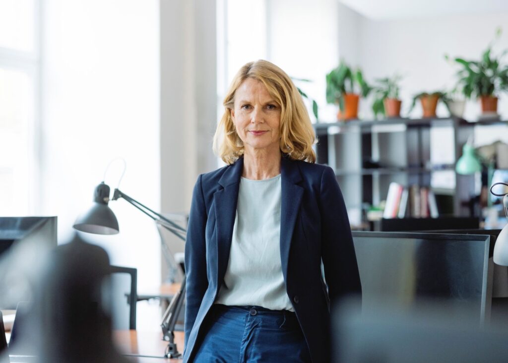 A woman in a suit stands looking confidently into the camera, the image depicts the confidence to discuss corporation tax following the autumn 2026 Budget